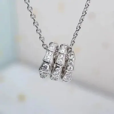 A silver chain necklace with a stacked pave ring pendant on a white background